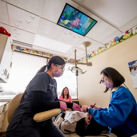Children's dentist and dental team member treating patient