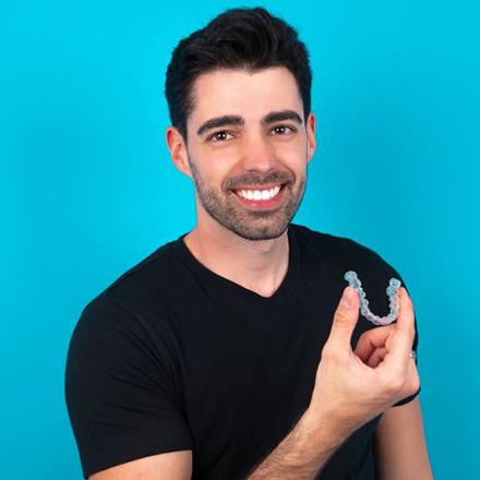 Man in black t-shirt holding Invisalign aligner