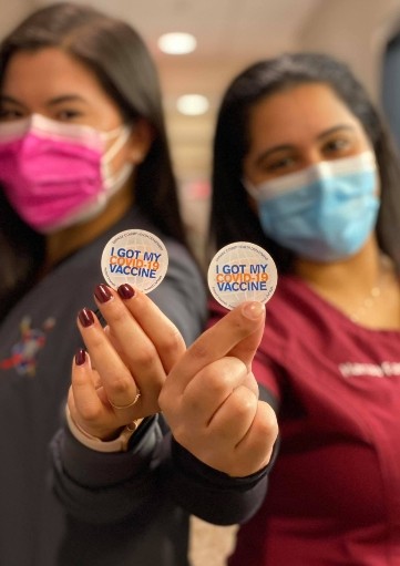 Two dental team members holding I got my vaccine stickers