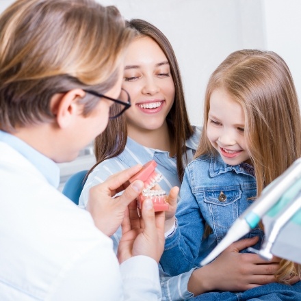 Pediatric dentist showing a smile model to mother and child