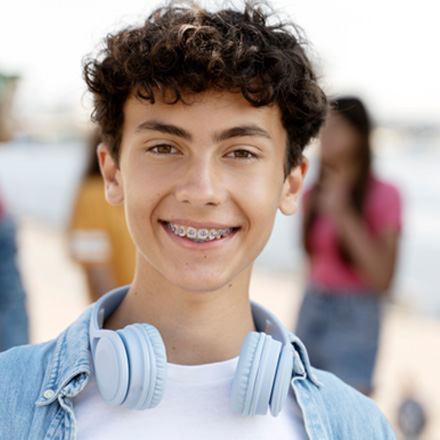 Male teenager wearing headphones and metal braces while smiling