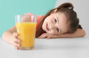 Child smiling while holding a glass of juice