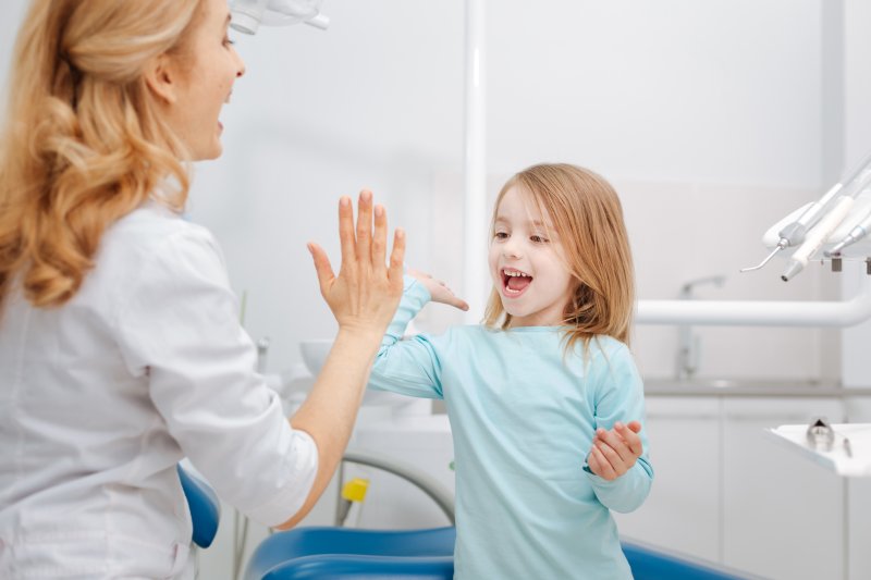 Young girl high-fiving dentist in exam room
