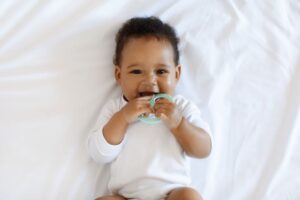 Smiling baby holding teething toy 