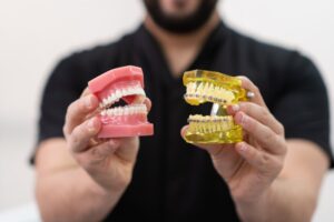 Man holding teeth models with braces and aligners